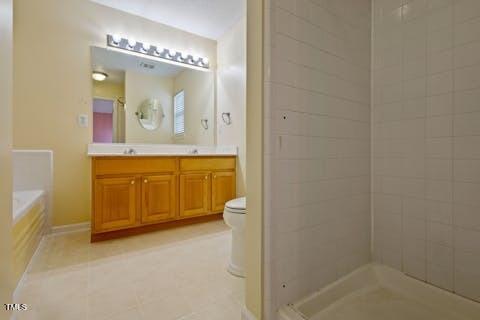 full bath featuring toilet, a shower, tile patterned flooring, double vanity, and a bath