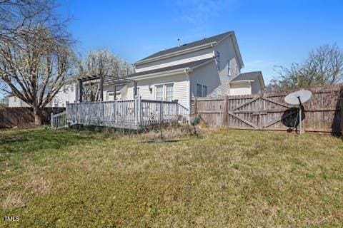 rear view of property with a yard, fence, and a wooden deck