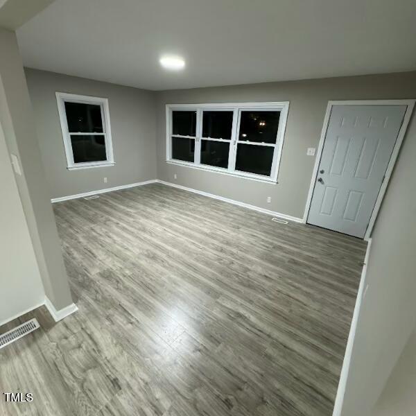 empty room featuring visible vents, baseboards, and wood finished floors