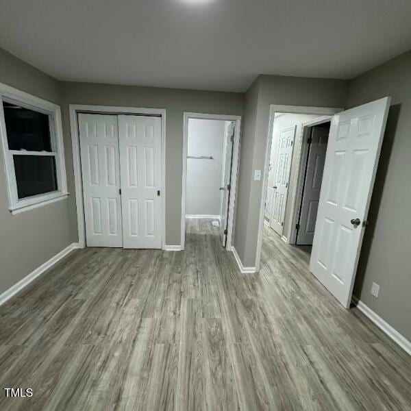 unfurnished bedroom with a closet, baseboards, and wood finished floors