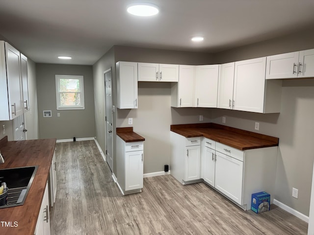 kitchen with white cabinets, light wood-style floors, baseboards, and wood counters