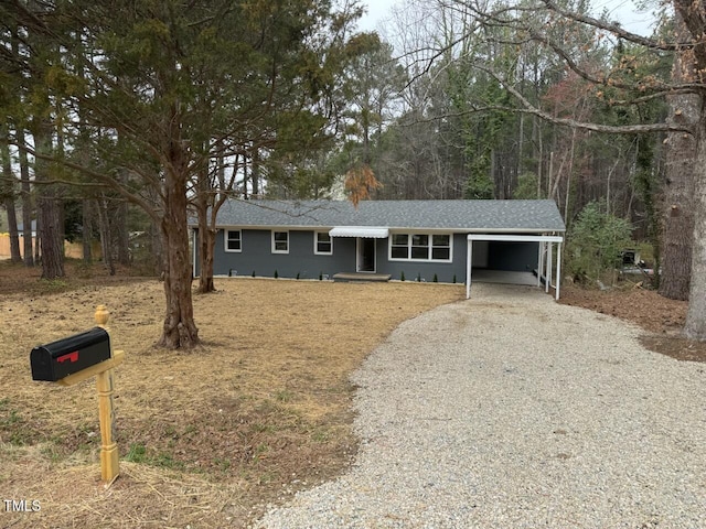 ranch-style house featuring an attached carport, driveway, and a shingled roof