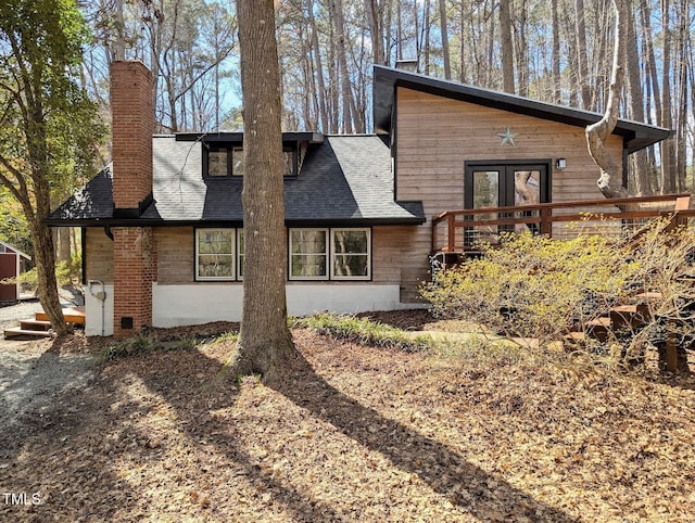 exterior space featuring french doors, a chimney, and a shingled roof