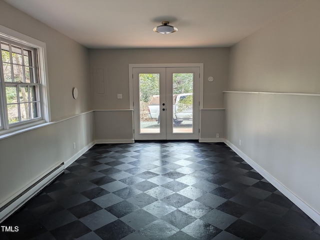 unfurnished room featuring a baseboard heating unit, french doors, and baseboards