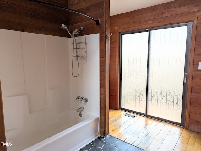 bathroom with wooden walls and washtub / shower combination