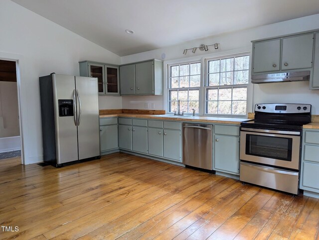 kitchen with under cabinet range hood, gray cabinets, appliances with stainless steel finishes, and a sink