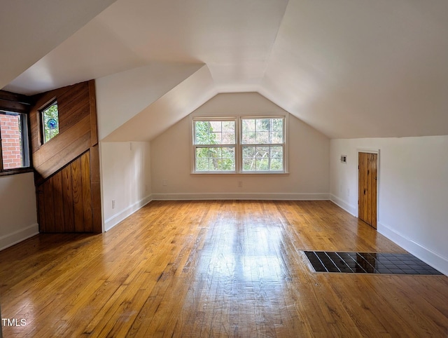 bonus room with light wood-type flooring, baseboards, and vaulted ceiling