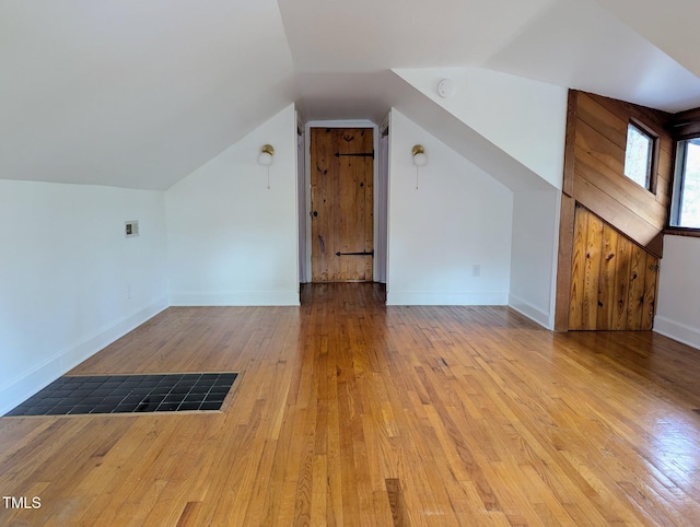 additional living space featuring hardwood / wood-style floors, lofted ceiling, and baseboards