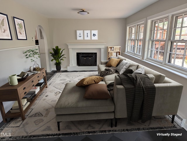 living area featuring baseboards, arched walkways, and a glass covered fireplace