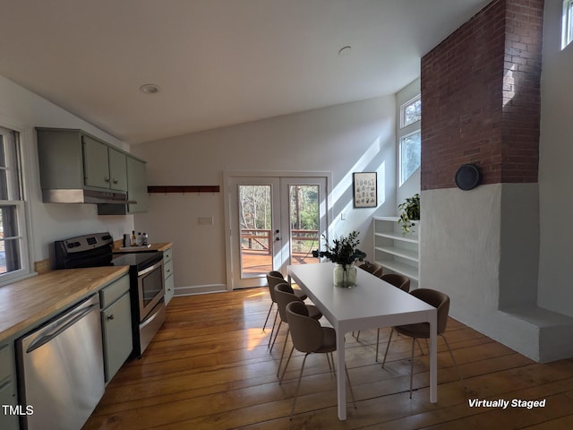 kitchen with a wealth of natural light, lofted ceiling, appliances with stainless steel finishes, and hardwood / wood-style flooring