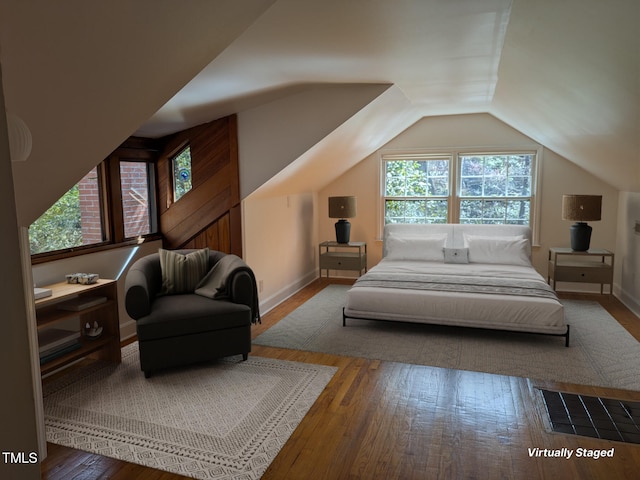 bedroom featuring hardwood / wood-style floors, lofted ceiling, and baseboards