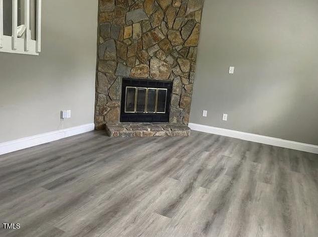 unfurnished living room featuring a fireplace, baseboards, and wood finished floors