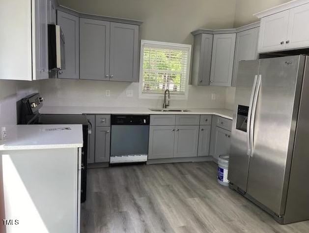 kitchen featuring black range with electric stovetop, gray cabinetry, a sink, stainless steel fridge, and dishwasher