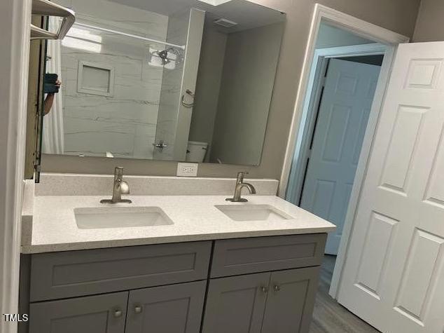 full bathroom with double vanity, toilet, and a sink