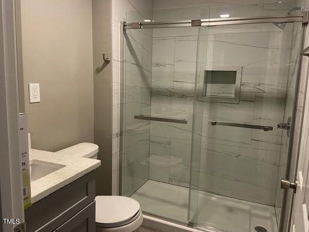 full bathroom with vanity, toilet, and a shower stall