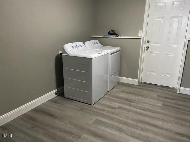 laundry area with baseboards, wood finished floors, washing machine and dryer, and laundry area