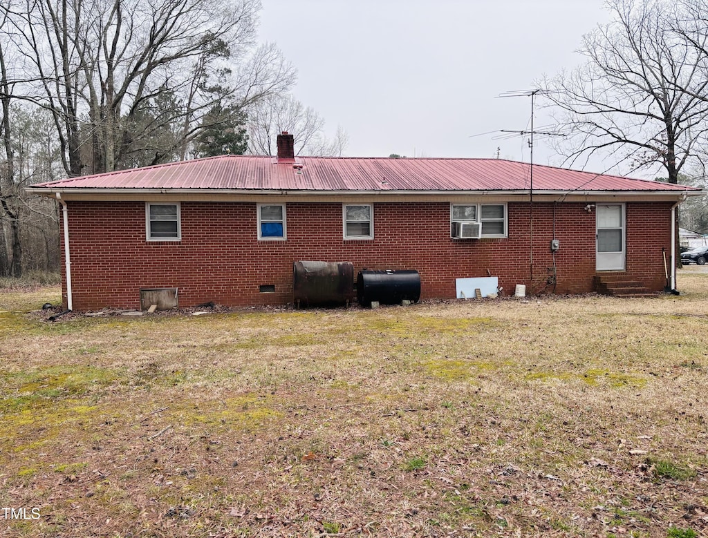 rear view of house with crawl space, a lawn, metal roof, and heating fuel