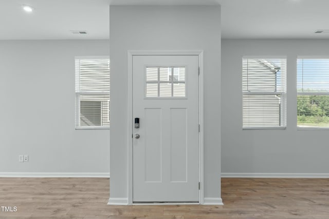 foyer entrance with light wood-style flooring, visible vents, and baseboards