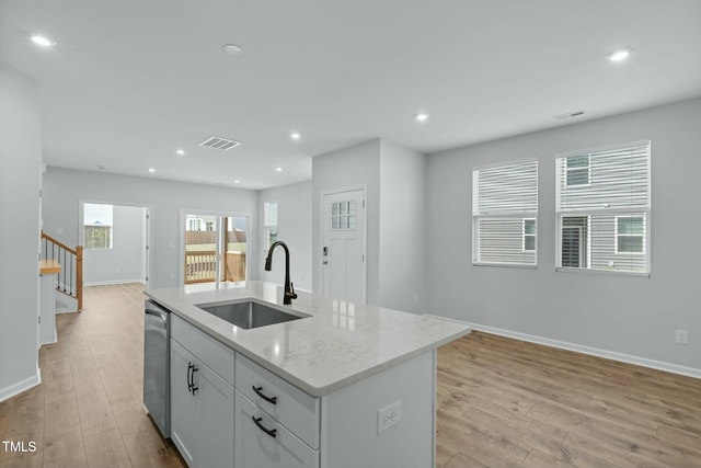 kitchen featuring light wood-type flooring, recessed lighting, a sink, stainless steel dishwasher, and open floor plan