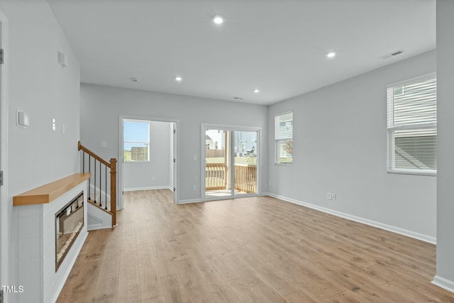 unfurnished living room featuring light wood-type flooring, visible vents, baseboards, and recessed lighting