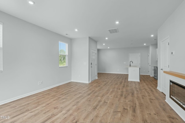 unfurnished living room with visible vents, recessed lighting, baseboards, and light wood-style floors