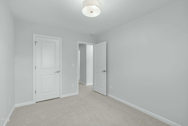 unfurnished bedroom featuring baseboards and light carpet