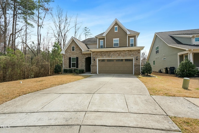 craftsman-style house featuring a garage, stone siding, concrete driveway, and a front yard