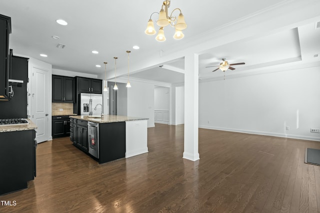 kitchen with open floor plan, stainless steel fridge, ceiling fan with notable chandelier, and dark cabinets