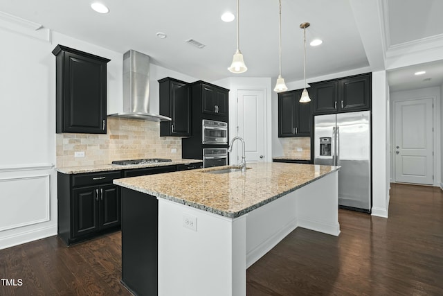 kitchen with visible vents, a sink, dark cabinetry, appliances with stainless steel finishes, and wall chimney range hood