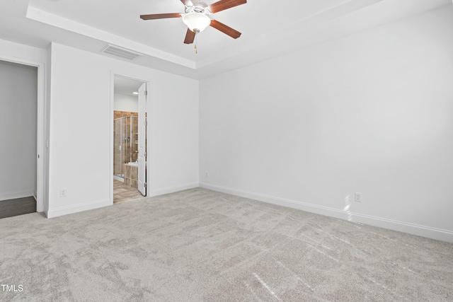 carpeted spare room featuring a raised ceiling, a ceiling fan, visible vents, and baseboards