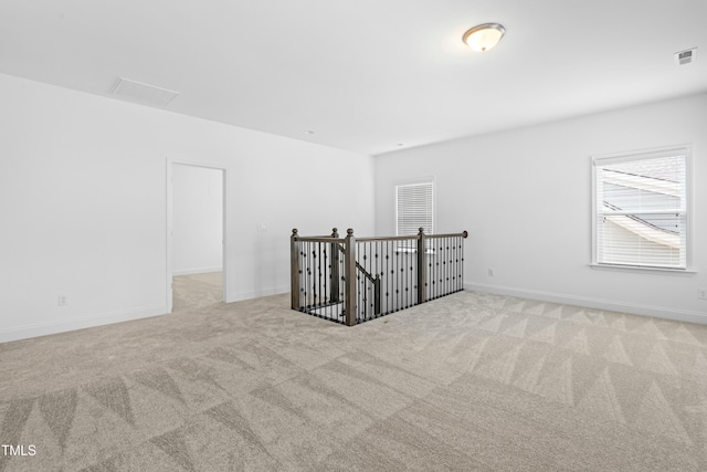 carpeted empty room featuring baseboards and visible vents