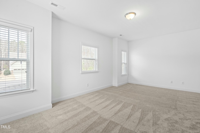 unfurnished room with plenty of natural light, carpet, visible vents, and baseboards