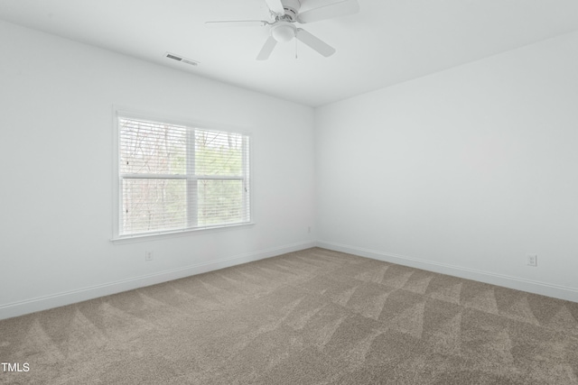 carpeted spare room featuring visible vents, a ceiling fan, and baseboards