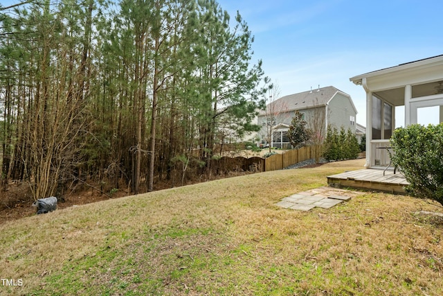 view of yard with a wooden deck, fence, and a sunroom