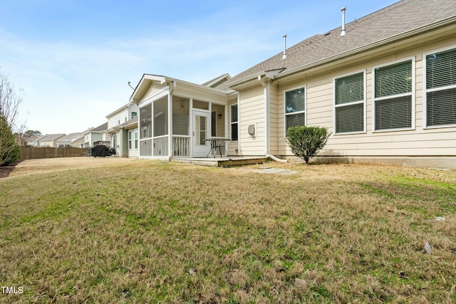 rear view of house with a yard, fence, a sunroom, and a shingled roof