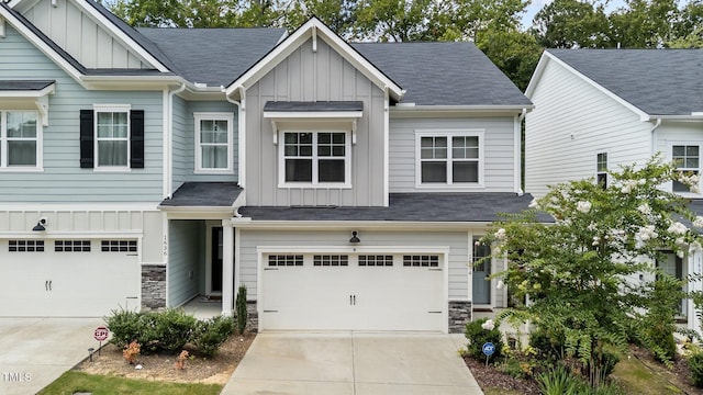 view of front facade featuring a garage, stone siding, and board and batten siding