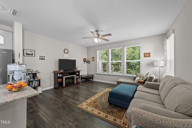 living room featuring a wealth of natural light, visible vents, dark wood-type flooring, and ceiling fan