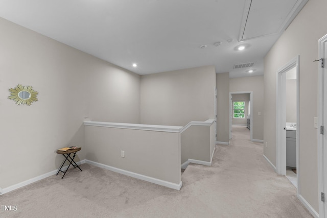 hall featuring visible vents, an upstairs landing, light carpet, baseboards, and attic access