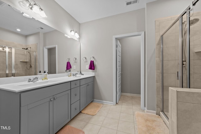 bathroom featuring a sink, double vanity, a stall shower, and tile patterned floors