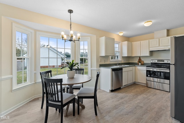 kitchen featuring light wood-style flooring, a sink, stainless steel appliances, a textured ceiling, and a chandelier