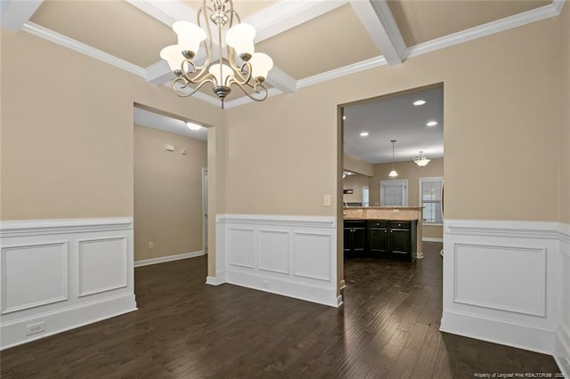 unfurnished dining area with crown molding, a chandelier, wainscoting, dark wood-style floors, and a decorative wall