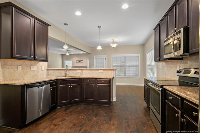 kitchen featuring a sink, stainless steel appliances, dark brown cabinetry, and a peninsula