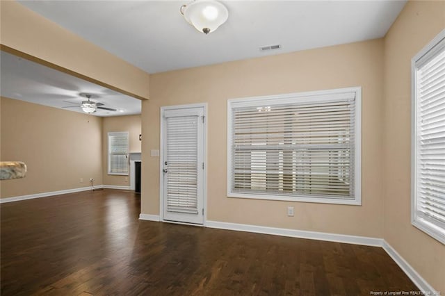 empty room with visible vents, baseboards, dark wood-style floors, and a ceiling fan