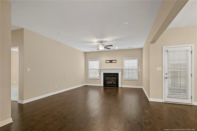 unfurnished living room with dark wood-style floors, baseboards, and a ceiling fan