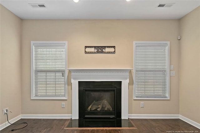 interior details featuring visible vents, a fireplace with flush hearth, and wood finished floors