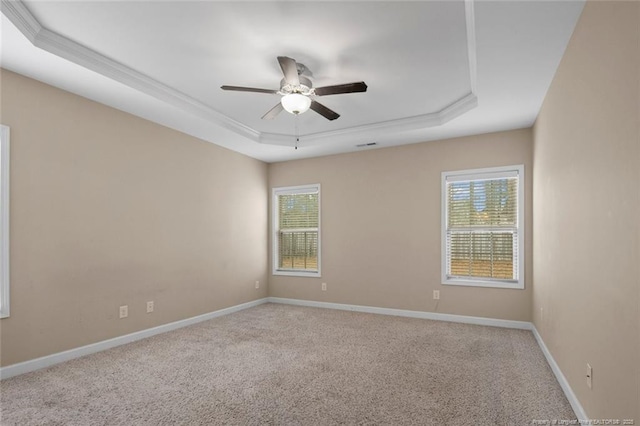 carpeted spare room featuring a tray ceiling, baseboards, a wealth of natural light, and ceiling fan