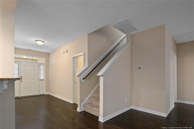 foyer with dark wood finished floors, visible vents, stairs, and baseboards