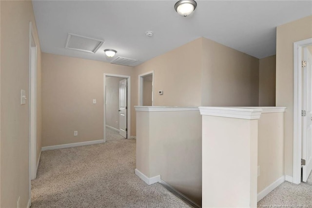 hallway featuring attic access, carpet flooring, and baseboards