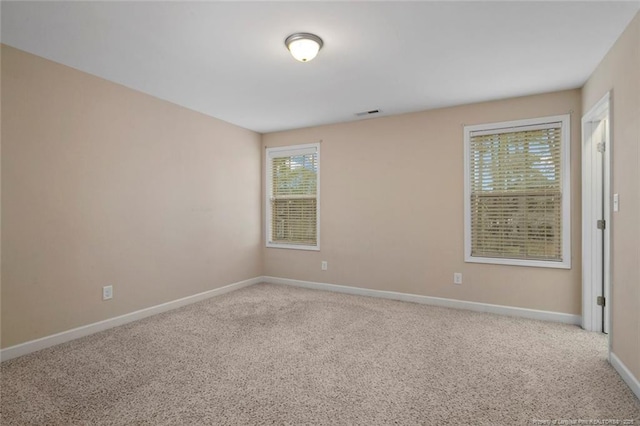 unfurnished room featuring carpet flooring, visible vents, and baseboards