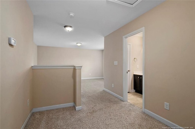 hall with baseboards and light carpet